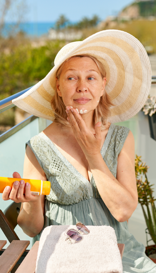 Image of a woman in a sun hat applying sun screen
