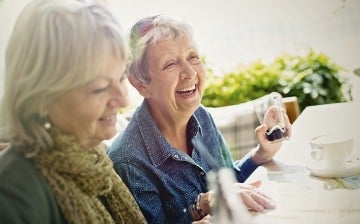 Two senior women drinking beverages at a table