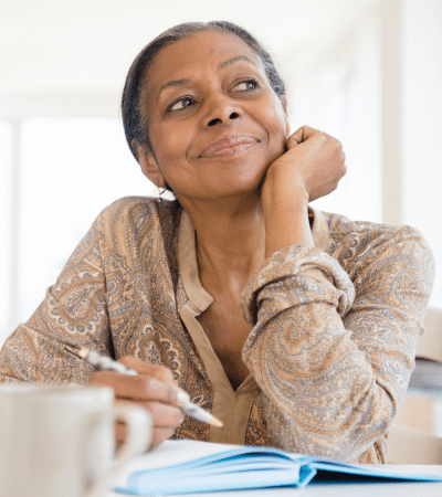 Woman thinking while writing in a notebook